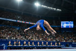 A blue leotard with sparkling embellishments worn by a female gymnast mid-air during a performance