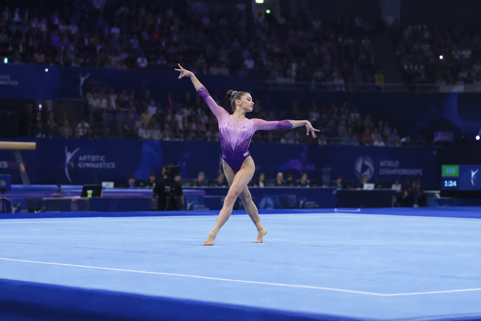 A purple and pink gradient leotard with sleek form fitting design worn by a gymnast in gymnastics floor competitions