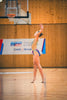 Young gymnast performs a graceful routine on wooden floor.