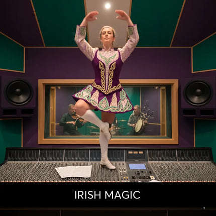 A woman in a vibrant purple and green celtic dance costume stands on an audio console for irish magic gymnastics floor music